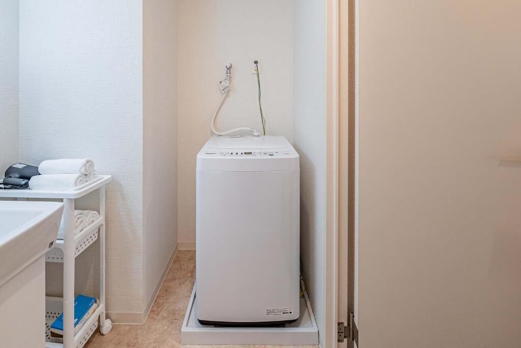 A white portable heater in a bathroom with a white shelf containing towels and a blue book.