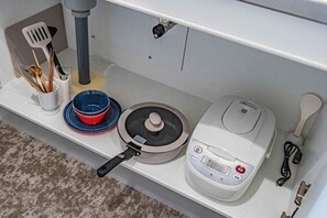 A kitchen with a rice cooker, a pot, a bowl, and utensils on a shelf. - Hoshi noYado Imamiya (Osaka)