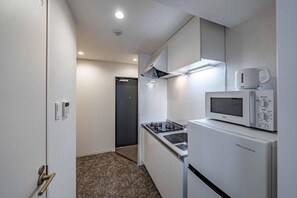 Una cocina funcional con microondas, estufa y refrigerador.