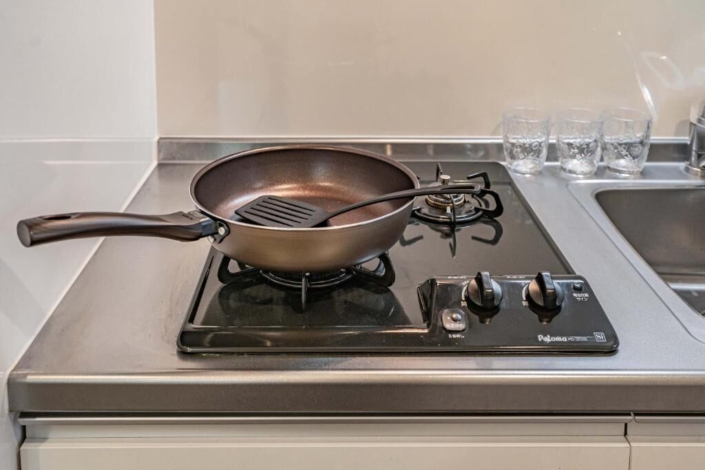 A kitchen with a gas stove, a frying pan, and a spatula.