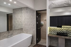A modern bathroom with a freestanding bathtub, a mirror, and a vanity with a patterned backsplash. - Hearium Hotel (Busan)