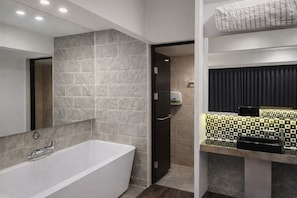 A modern bathroom with a freestanding bathtub, a mirror, and a vanity with a patterned backsplash. - Hearium Hotel (Busan)