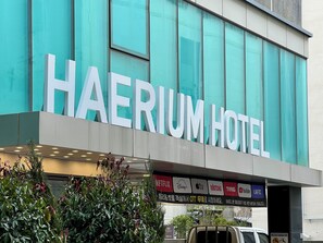Het uiterlijk van Hotel Haerum met grote borden, een modern architectonisch ontwerp en een bord met diverse streamingdiensten.