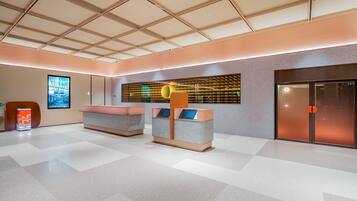 Un vestíbulo moderno con piso a cuadros, una recepción, una pantalla digital y una puerta.