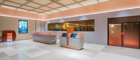 Un vestíbulo moderno con piso a cuadros, una recepción, una pantalla digital y una puerta.