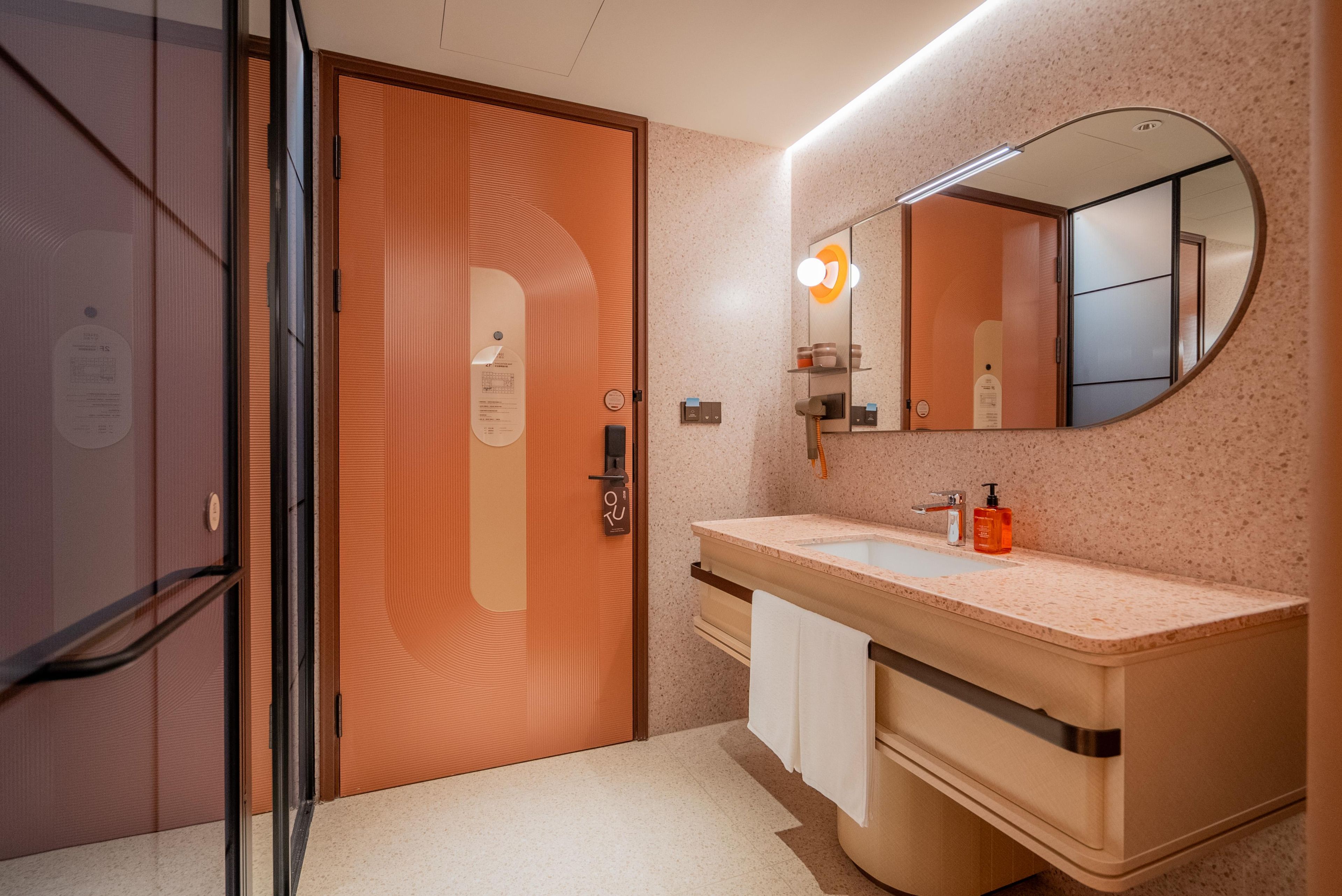 Un baño moderno con puerta de madera, un lavabo con espejo y un perchero para toallas.