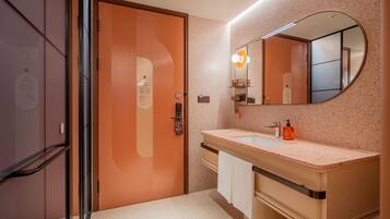 Un baño moderno con puerta de madera, un lavabo con espejo y un perchero para toallas.