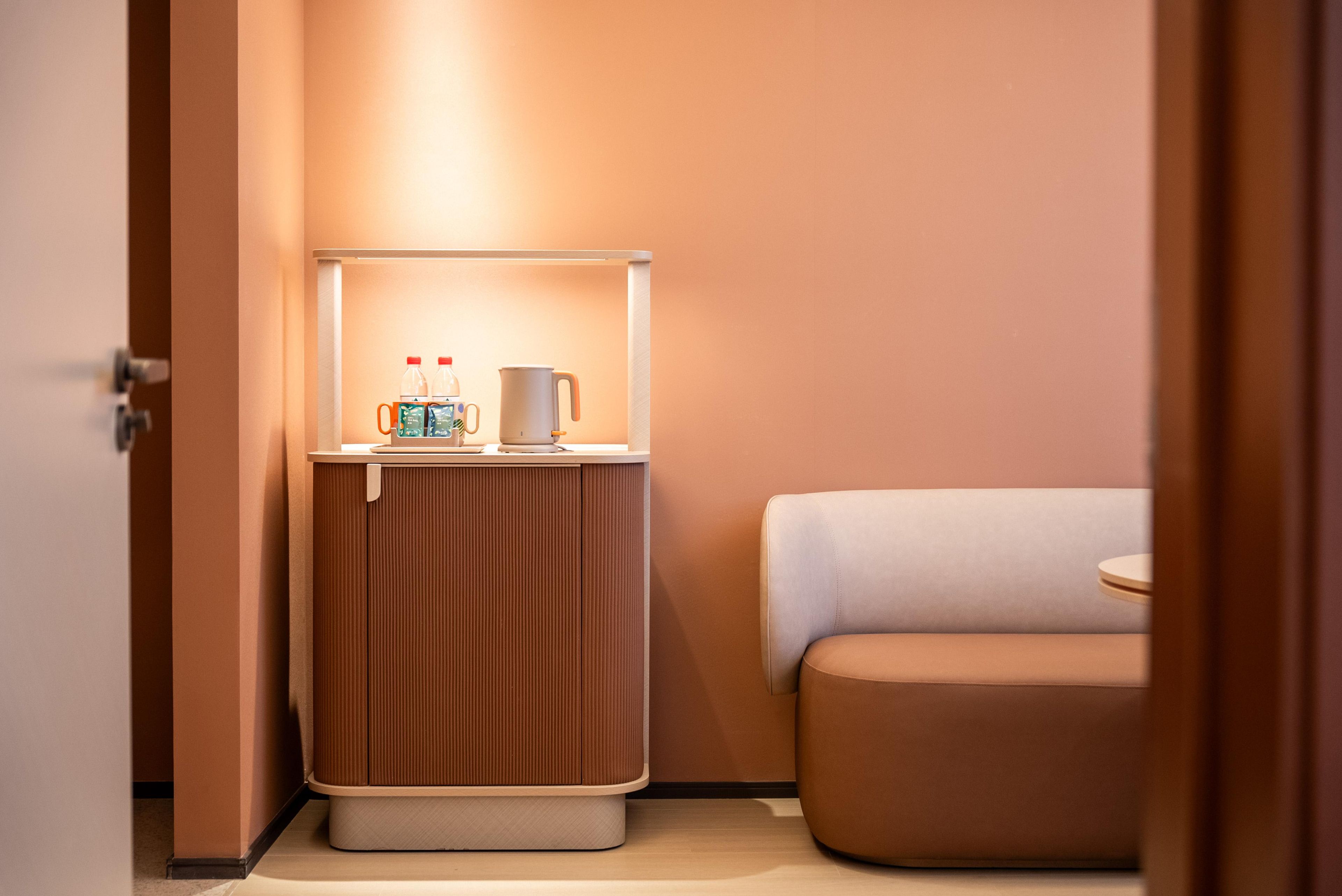 Une chambre d’hôtel de taille réduite, comprenant une table de chevet, une petite armoire avec une lampe et un lit.