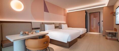 A modern hotel room with a large bed, a desk with a chair, and a small table.