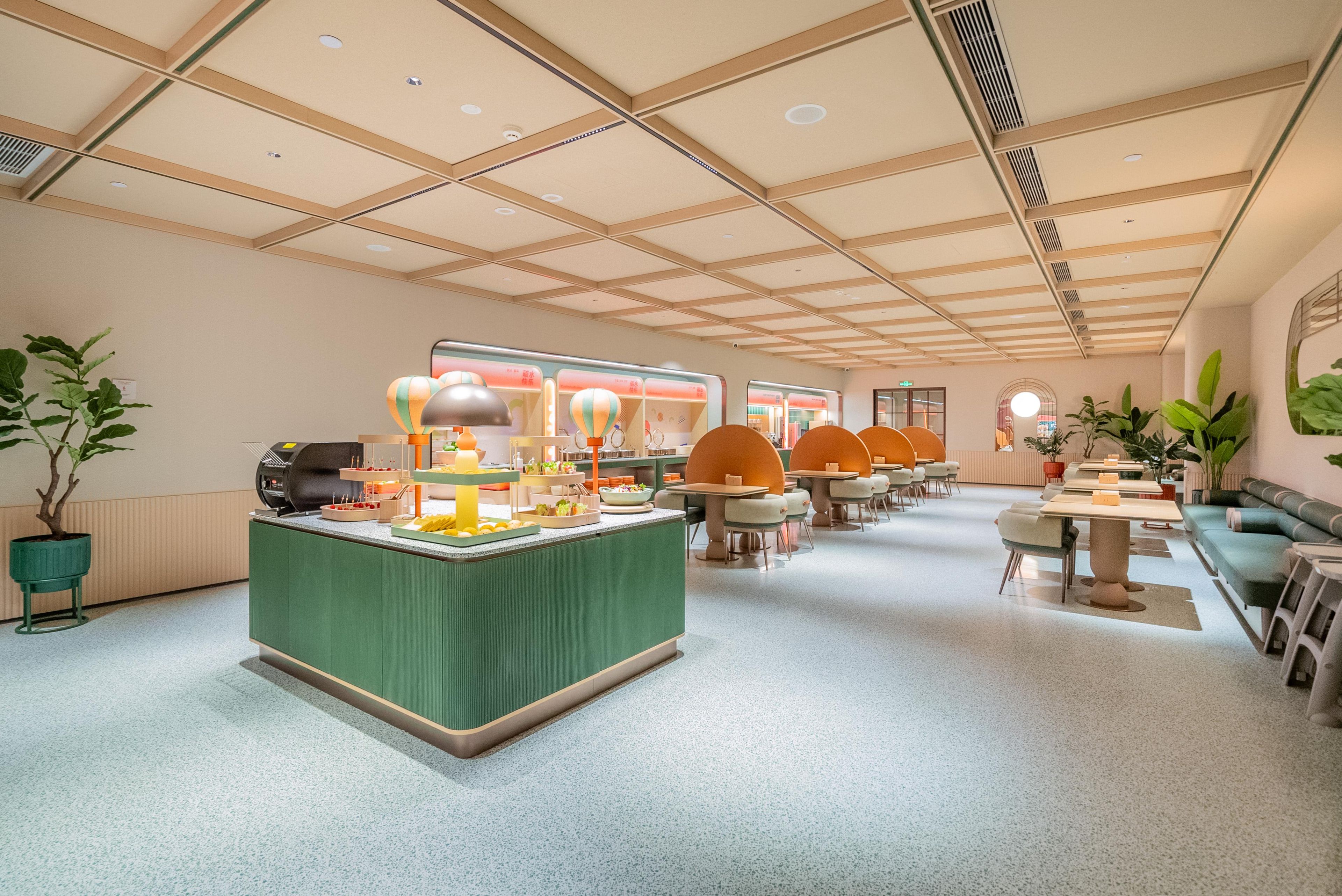 A modern interior with a central serving area, multiple seating arrangements, and a high ceiling with recessed lighting.