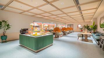 A modern interior with a central serving area, multiple seating arrangements, and a high ceiling with recessed lighting.