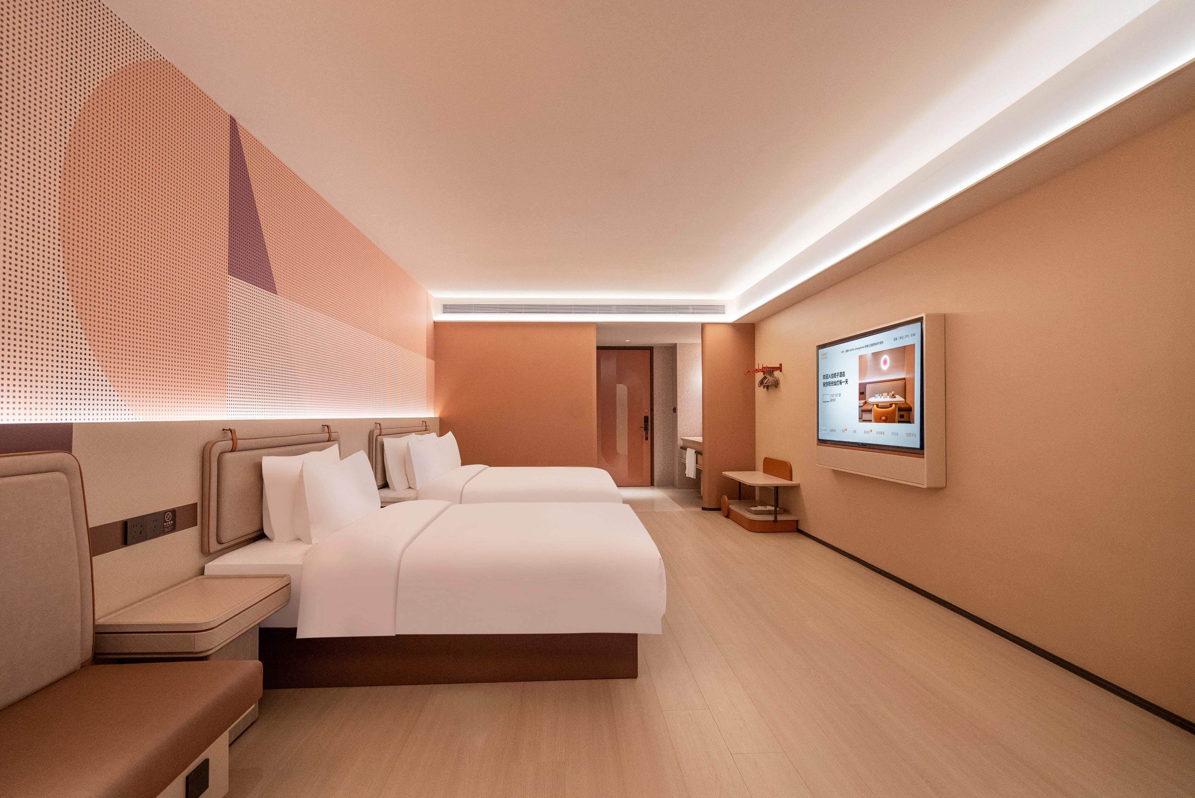 A hotel room with two beds, a seating area, a TV, and a bathroom visible in the background.