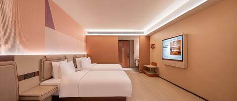 A hotel room with two beds, a seating area, a TV, and a bathroom visible in the background.