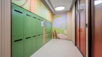 Un pasillo con taquillas verdes, un mural en la pared y una puerta con picaporte.