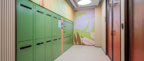 A hallway with green lockers, a wall mural, and a door with a handle.