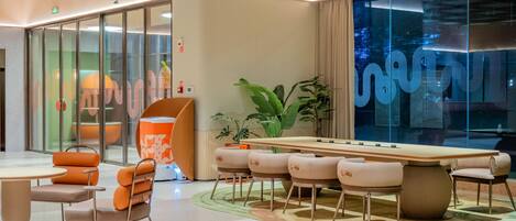 A modern conference room with a long table, multiple chairs, and a glass partition.