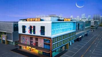 A modern hotel with a prominent sign, large windows, and a parking lot.