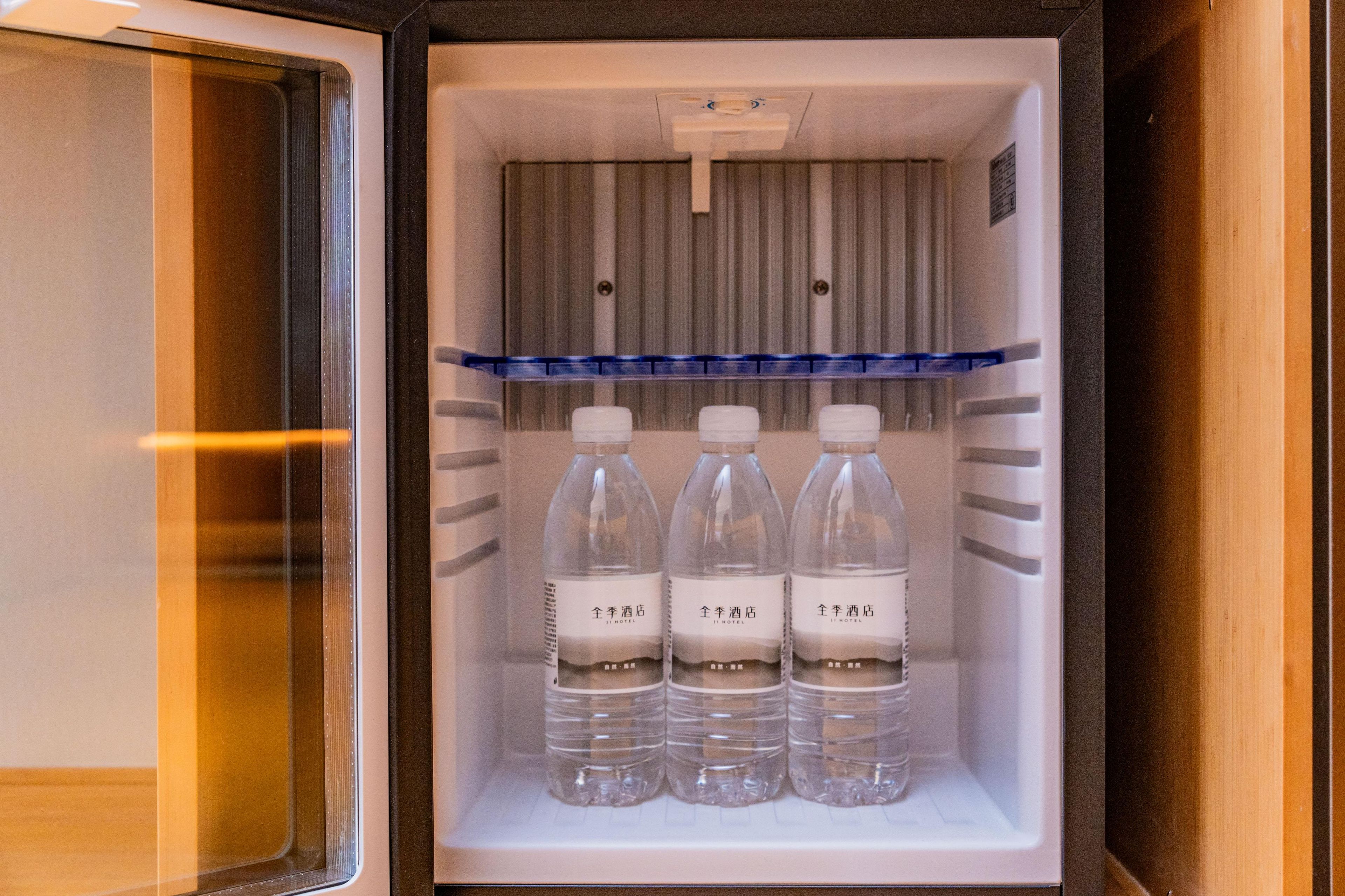 A mini-fridge with three bottles of water, a blue tray, and a white label with text.