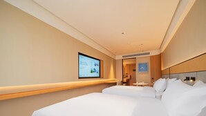 Una habitación de hotel con una cama grande, un televisor montado en la pared y una pequeña mesa con una silla.
