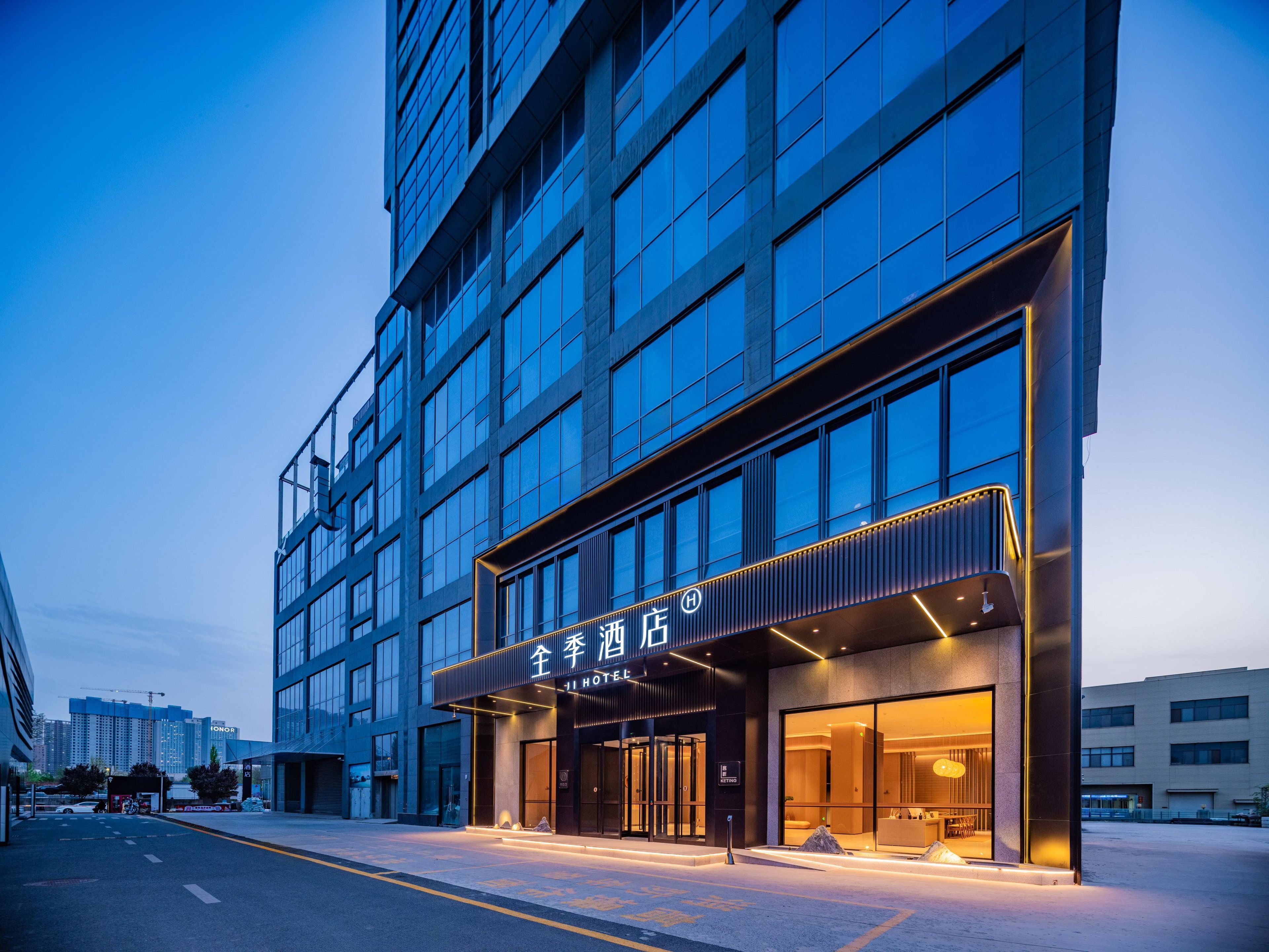 Een modern hotel met een glazen gevel, een opvallende ingang en een goed verlichte buitenkant.