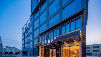 A modern hotel with a glass facade, a prominent entrance, and a well-lit exterior.