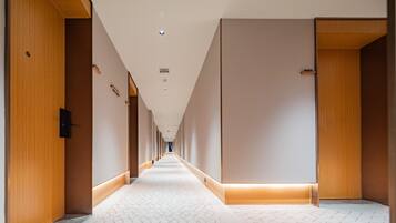 A long, narrow hotel corridor with wooden doors on either side and a patterned carpet.