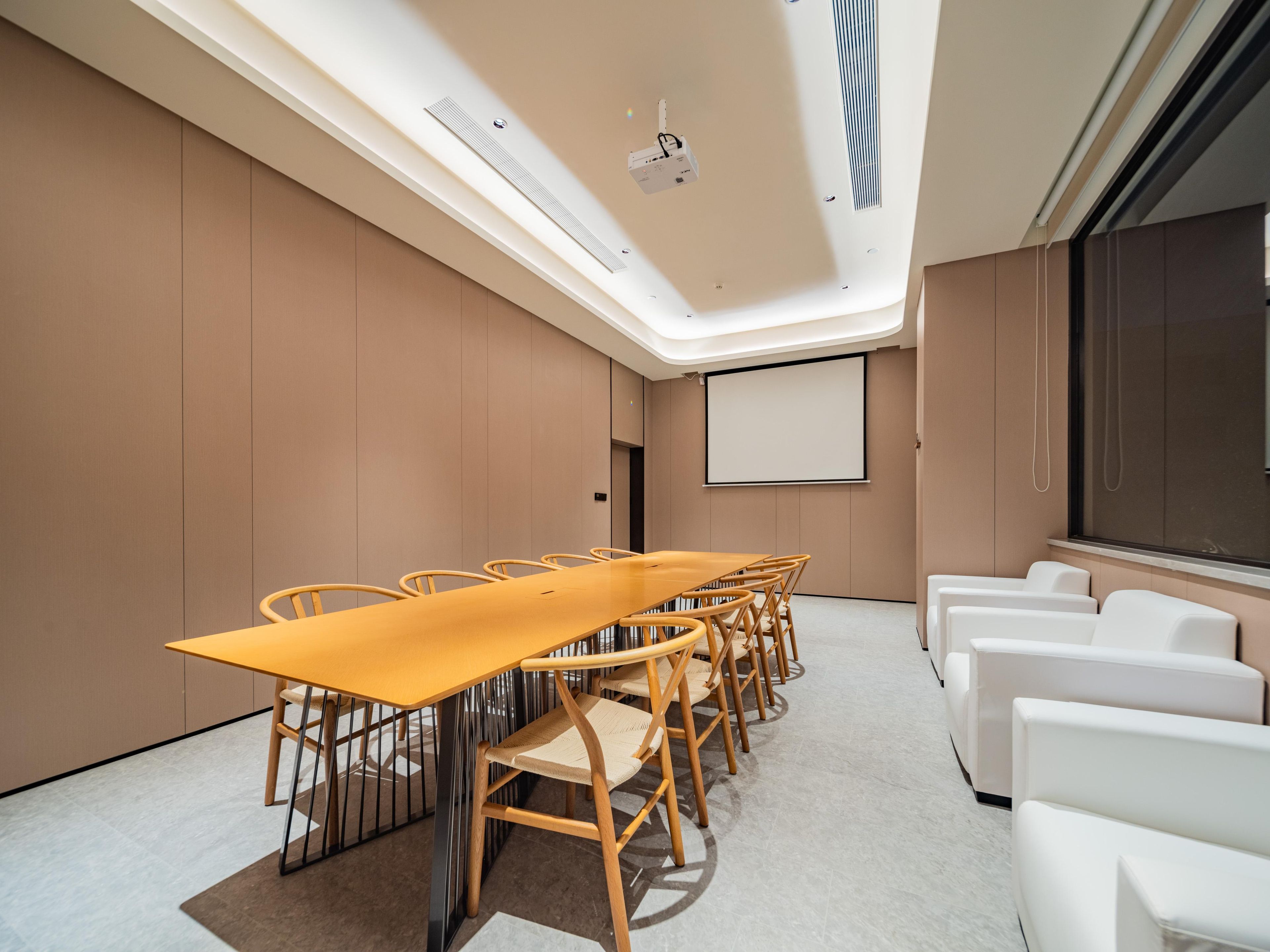 A conference room with a long table, chairs, a projector screen, and a large window.