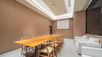 A conference room with a long table, chairs, a projector screen, and a large window.