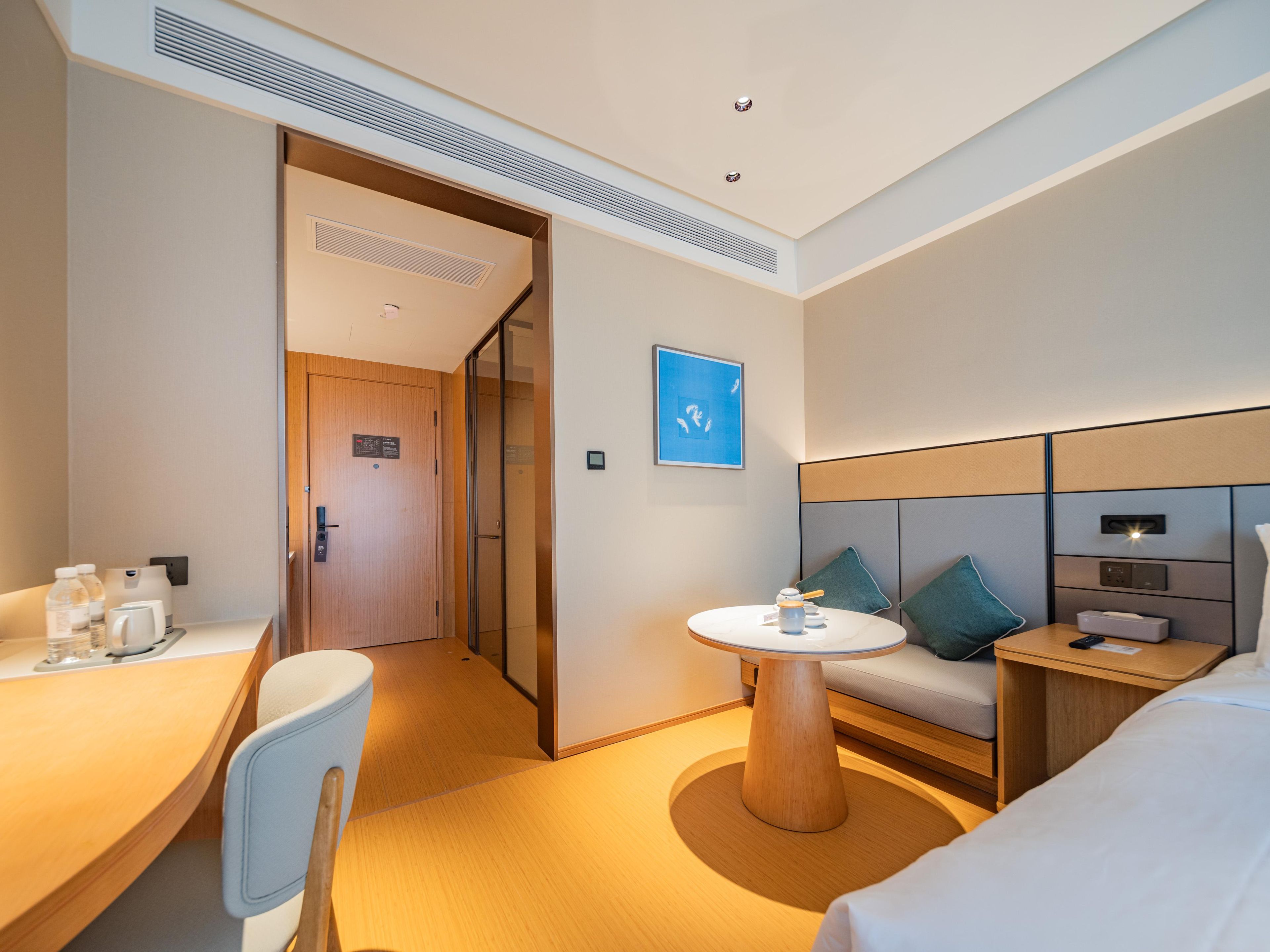 A hotel room with a bed, a desk, a chair, a round table, and a sofa.