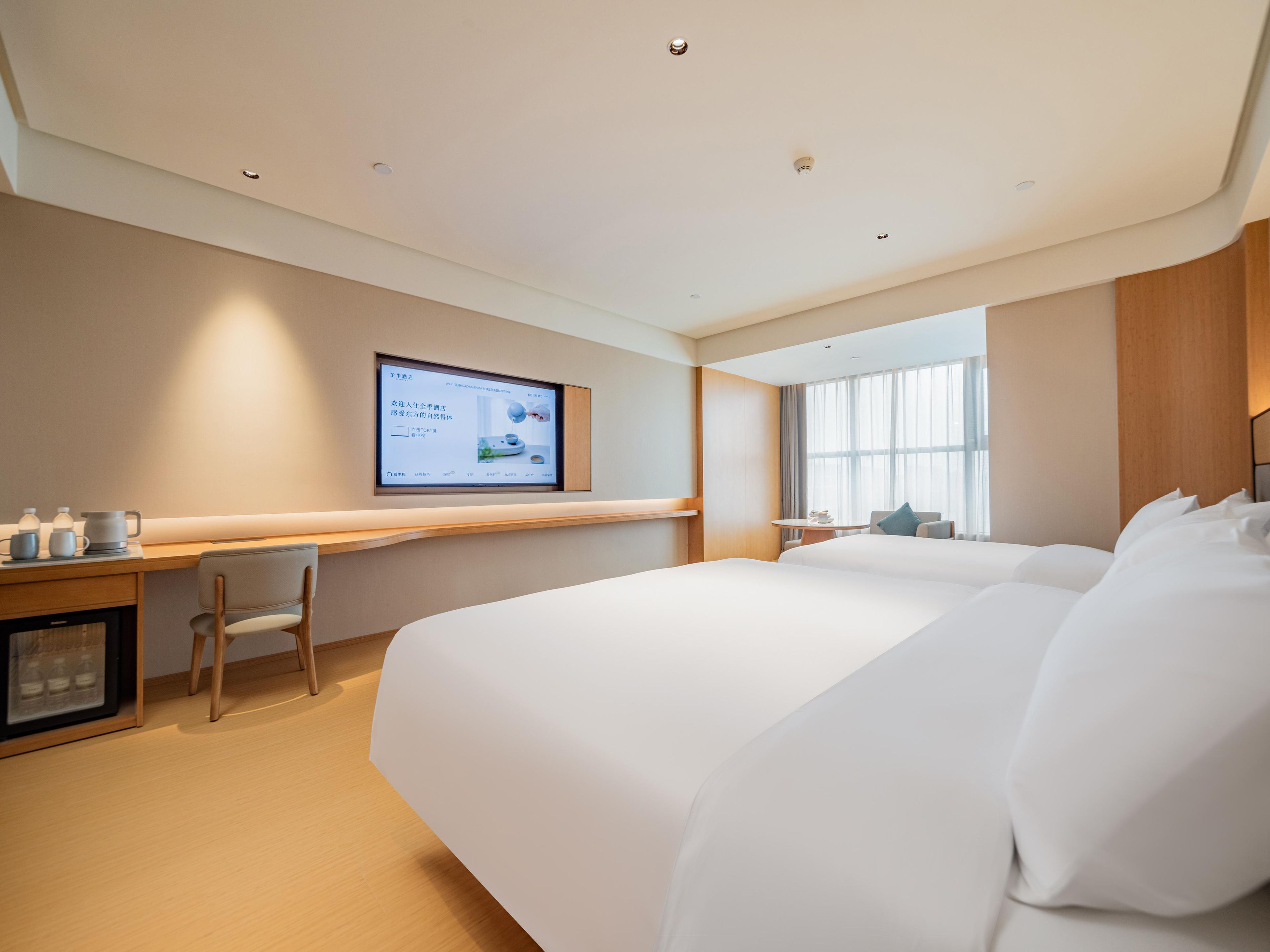 Une chambre d’hôtel avec un grand lit, un bureau avec un ordinateur et un téléviseur fixé au mur.