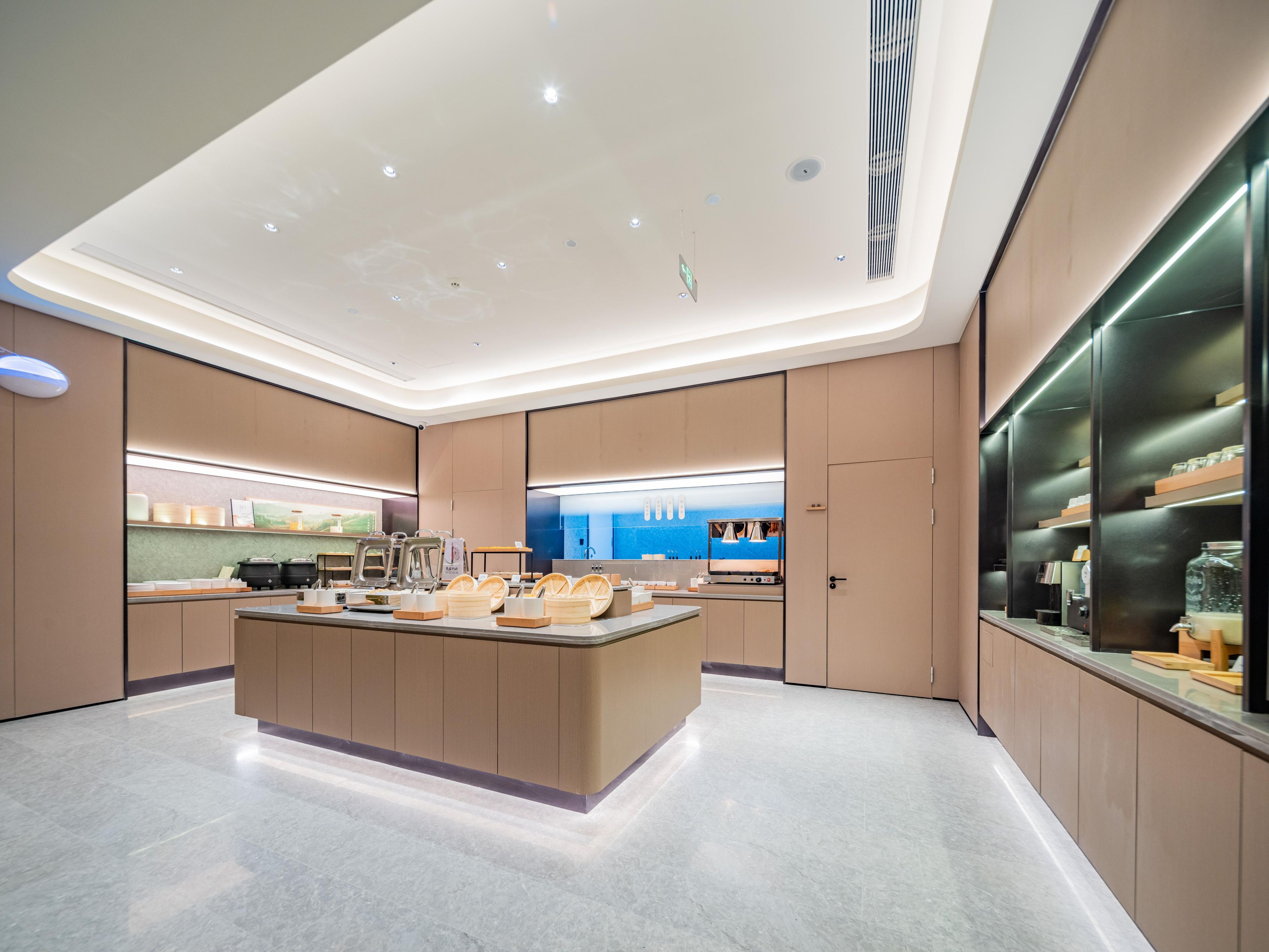 Une cuisine moderne dotée d’un îlot central, d’appareils électroménagers intégrés et offrant une vue sur la mer.