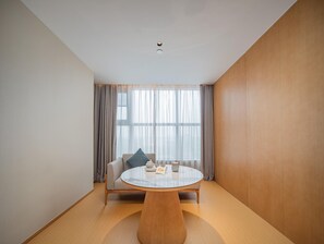 A modern room with a round table, a sofa, and a large window with curtains. - JI Hotel Xian National Supercomputing Center East (Xi'an)