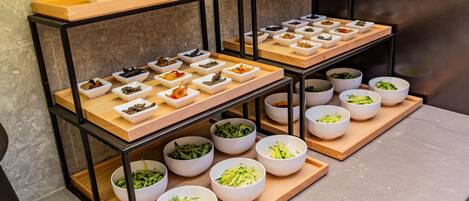 A buffet setup with various food items arranged on wooden boards and white bowls.