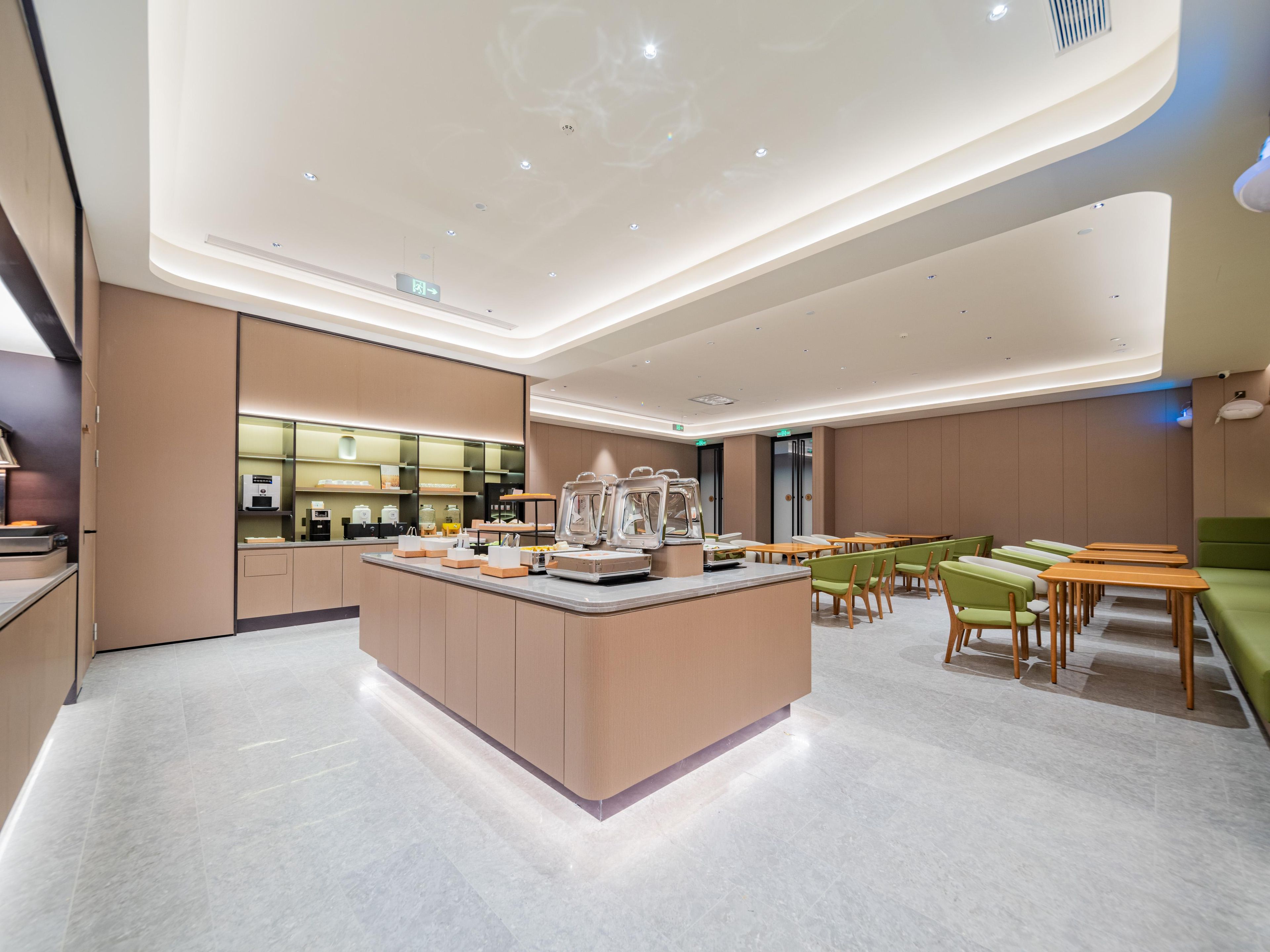 A modern hotel lobby with a central island, seating area, and a reception desk.
