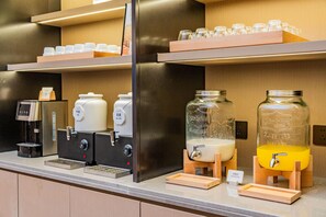 Una estación de autoservicio para bebidas con dispensadores de leche, leche de soya y jugo.