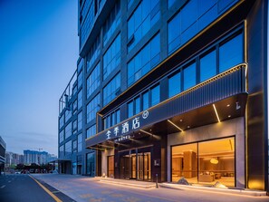 Un hotel moderno con una entrada destacada y un amplio frente de vidrio.