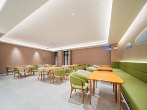 A modern conference room with multiple tables and chairs, a green sofa, and a ceiling with recessed lighting. - JI Hotel Xian National Supercomputing Center East (Xi'an)