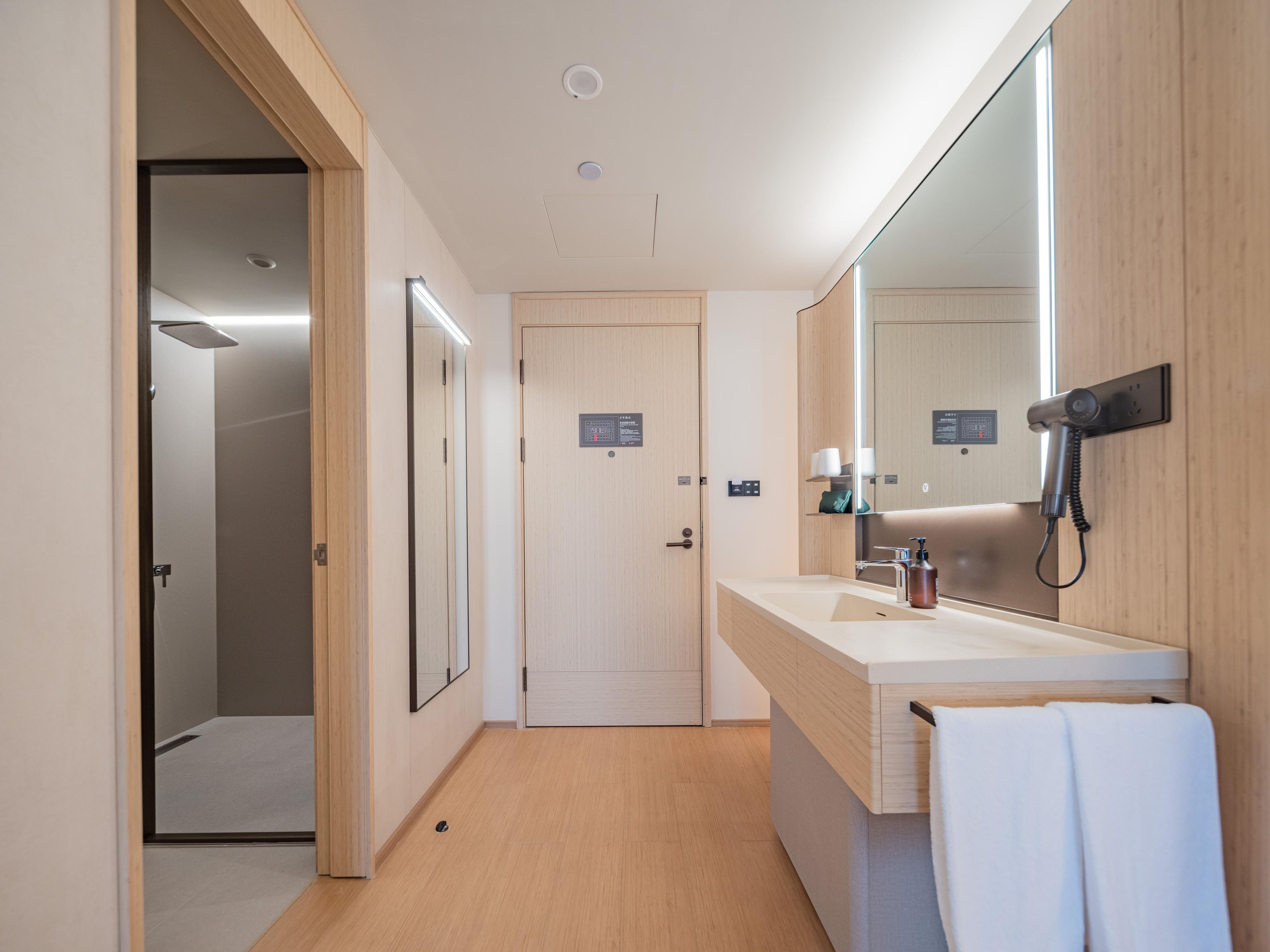 A modern bathroom with a shower, a sink with a mirror, and a towel rack.