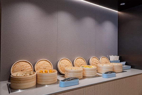 Un mostrador de buffet con varias vaporeras de bambú que contienen diferentes alimentos.