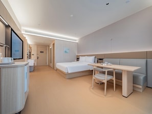 A modern hotel room with a bed, a desk, and a seating area. - JI Hotel (Xi'an)