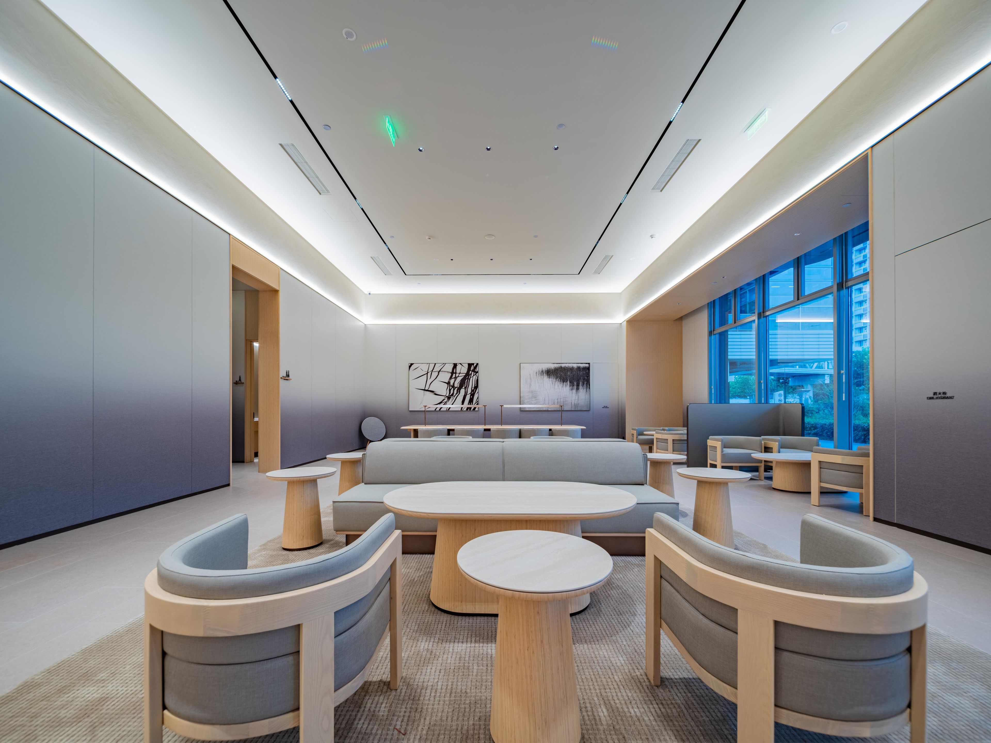 A modern interior with a central seating area, round tables, and a large window providing a view.