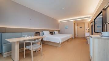 A hotel room with a bed, a desk, a chair, a bedside table, and a mirror.