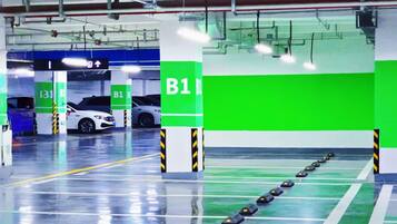 A parking garage with green and white pillars, clear directional signage, and a clean, reflective floor.