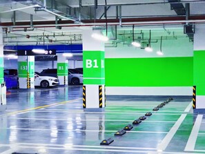 Een parkeergarage met groene en witte pilaren, duidelijke bewegwijzering en een schone, reflecterende vloer.