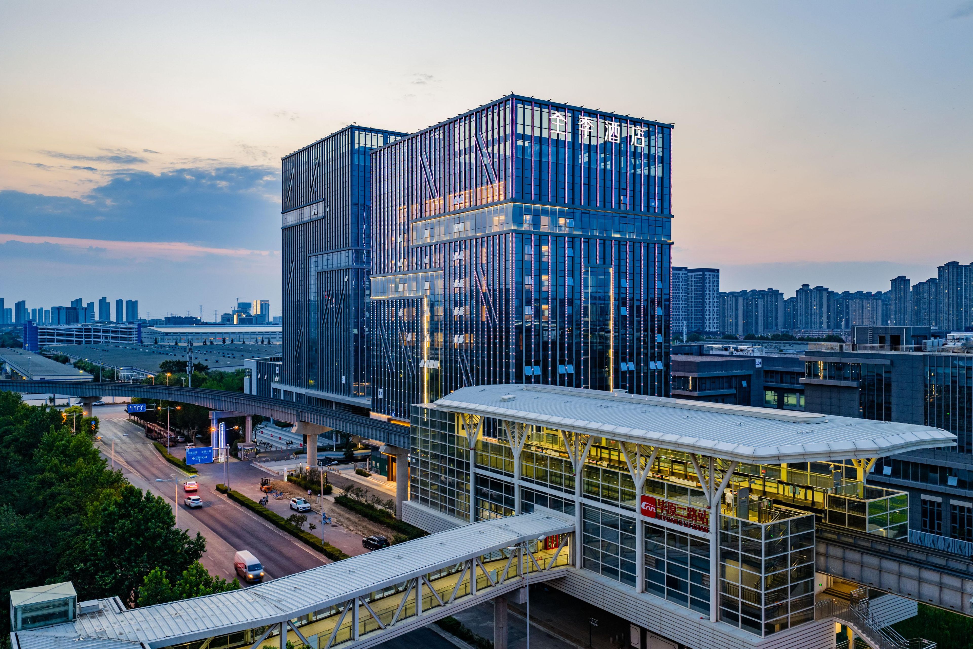A modern hotel with a glass facade, located in an urban setting with a view of the city skyline.