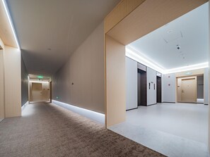 A modern hallway with carpeted flooring, wooden paneling, and a ceiling with recessed lighting. - JI Hotel (Xi'an)