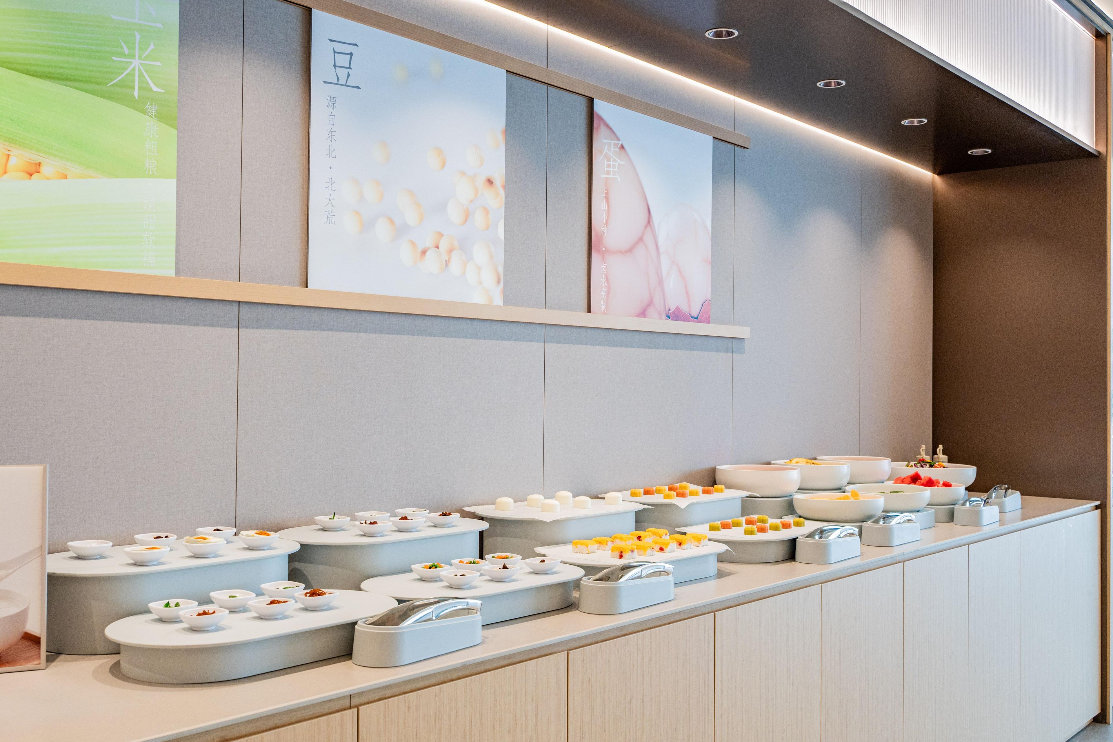 A buffet setup with various dishes and a wall with cultural posters.