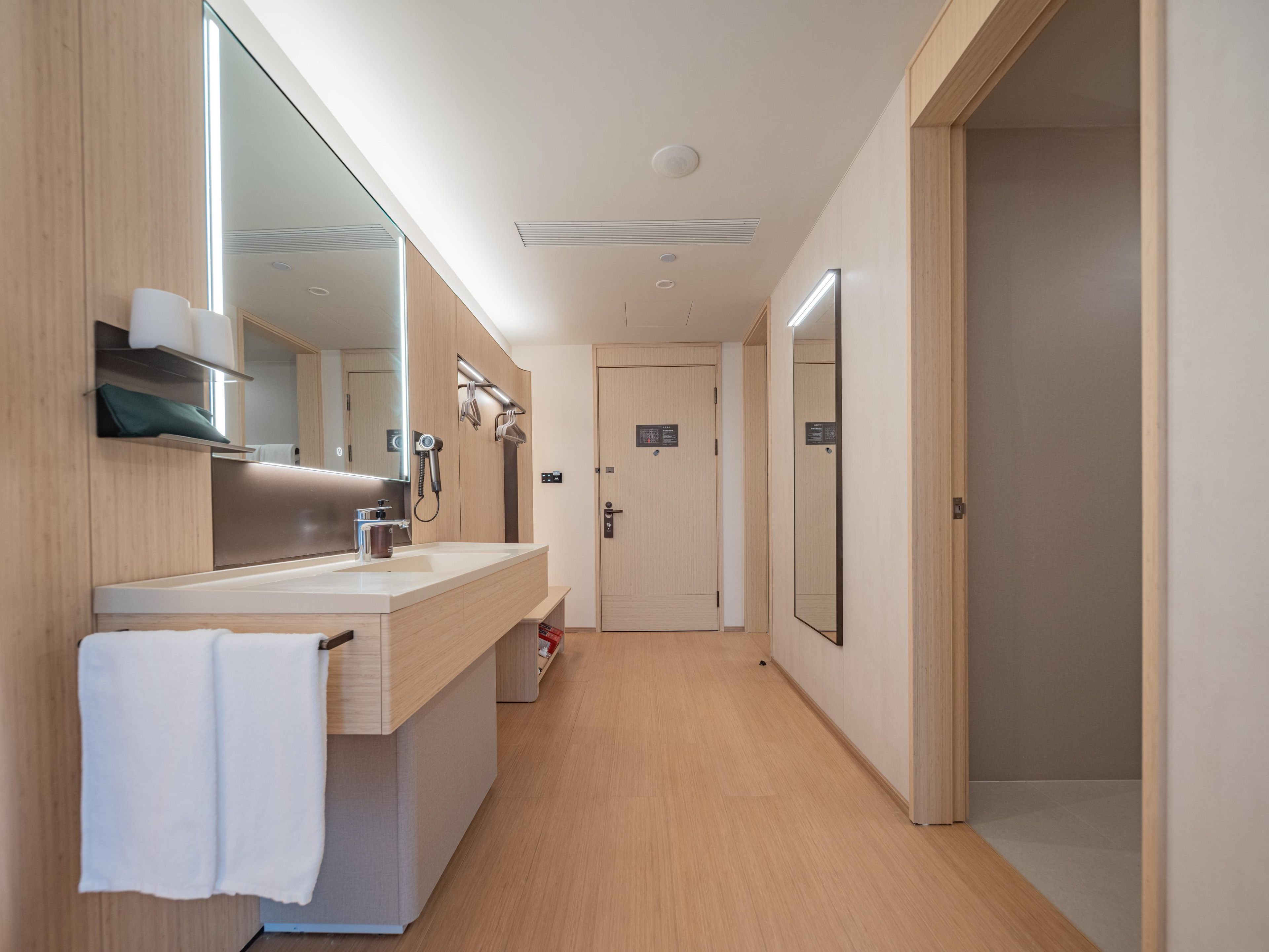 A modern bathroom with a large mirror, a sink, and a shower area.