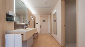 A modern bathroom with a large mirror, a sink, and a shower area.