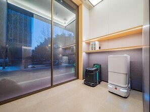Habitación de hotel moderna con un amplio ventanal corredero, un purificador de aire compacto y un calentador portátil blanco.